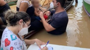 Trabalhadores na linha de frente: médico e assistente atendem população dentro da água no AC