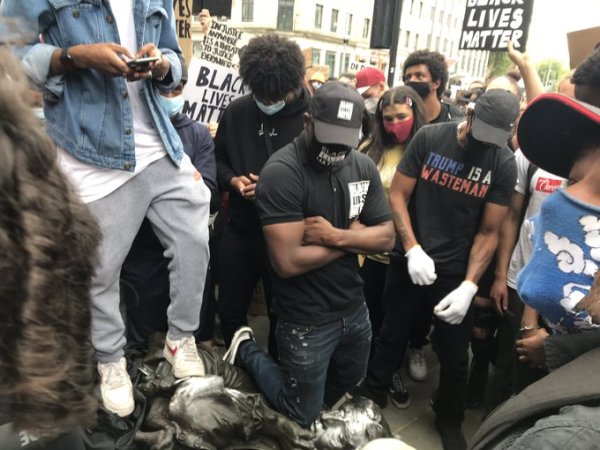 Em memória a George Floyd, manifestante negro ajoelha em pescoço de estátua de escravista